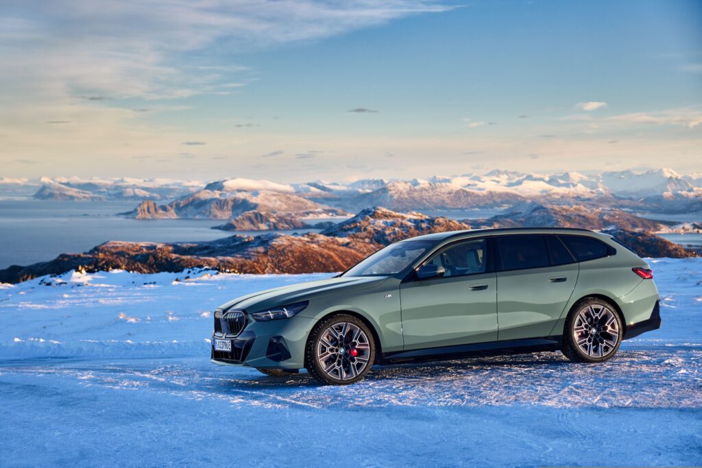 BMW i5 Touring in Grün, Frontansicht schräg im Schnee