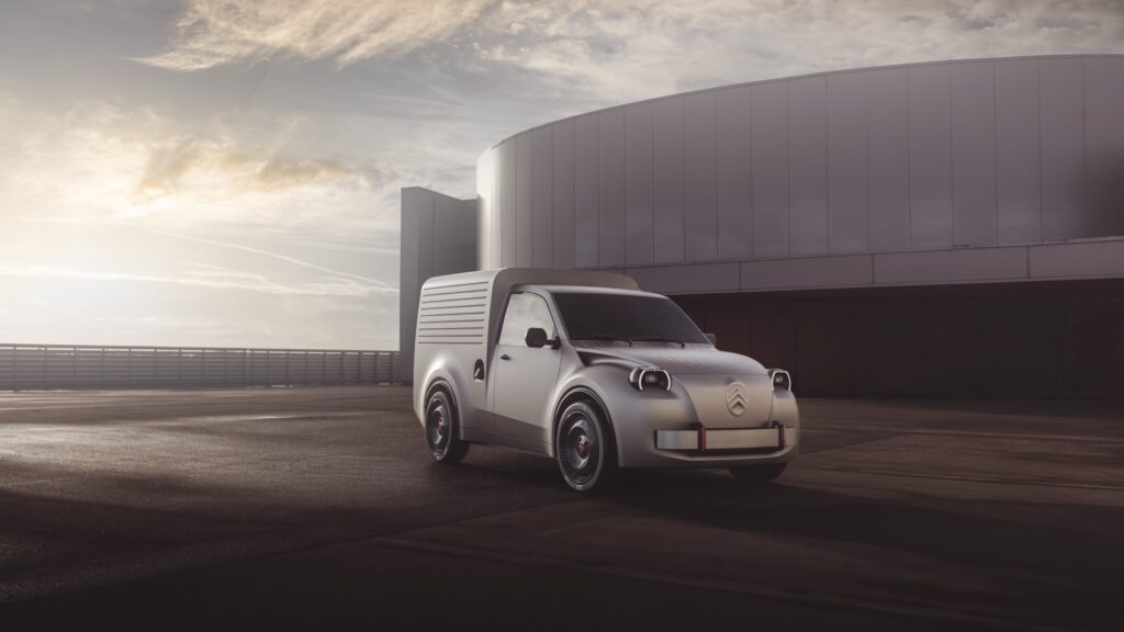 Silbergrauer Citroën 2CV Fourgonnette Concept mit Kastenaufbau und runden Scheinwerfern in Schrägansicht von vorn vor einem runden Hallenbau