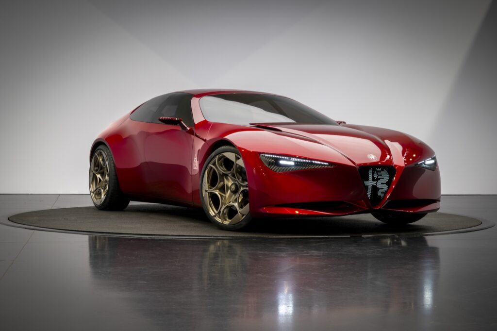 Roter Alfa Romeo Cuorerosso in Dreiviertel-Frontansicht mit beleuchtetem Scudetto-Kühlergrill und bronzefarbenen Leichtmetallrädern
