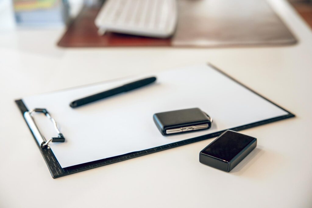 Klemmbrett mit Stift und zwei Autoschlüsseln auf einem Schreibtisch